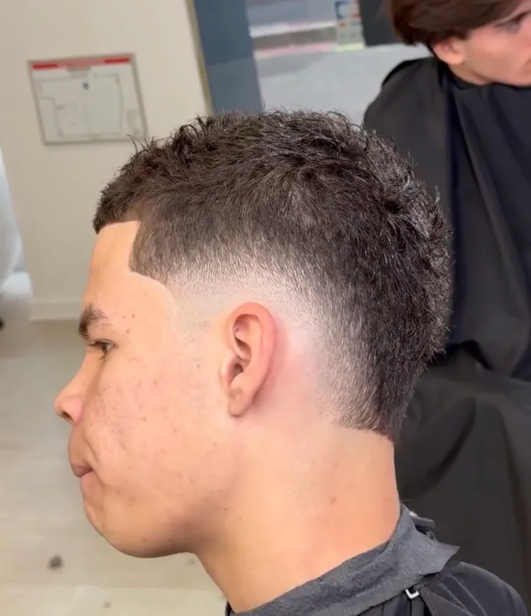 Coupe courte bouclée avec dégradé net sur les côtés